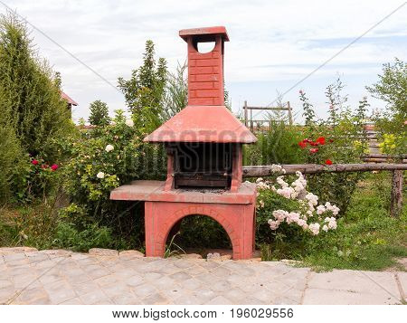 Barbecue In Summer Garden Among Trees And Beautiful Blooming Red, Pink And White Roses.