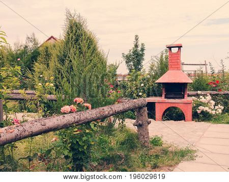 Barbecue In Summer Garden Among Trees And Beautiful Blooming Red, Pink And White Roses.
