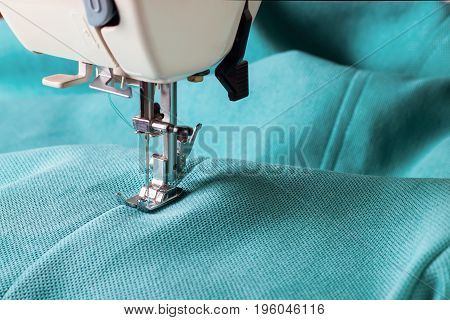 Close up of sewing machine working with turquoise fabric
