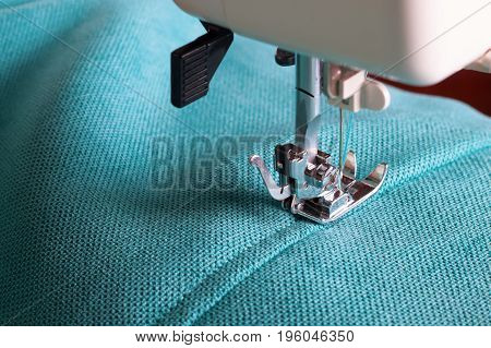 Close up of sewing machine working with turquoise fabric