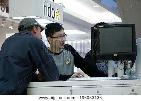 Burnaby, BC, Canada - April 03, 2017 : People asking fido sales clerk about cellphone plan inside Burnaby shopping mall