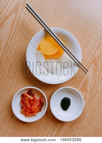 Top view of Korean kimchi pickles side dish on small white plates with chopsticks.