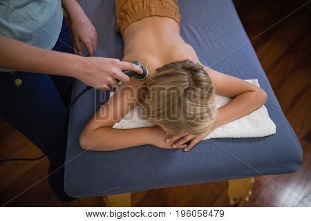 High angle view of female therapist using ultrasound machine on boy at hospital ward