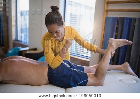 Young female therapist massaging buttocks of senior male patient at hospital ward