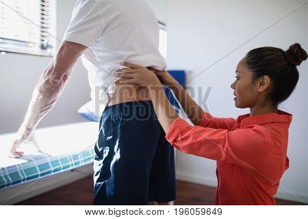 Side view of female therapist massaging back at hospital ward