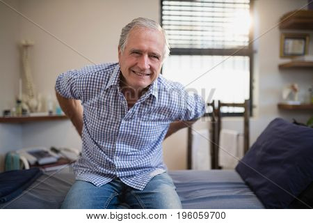 Senior male patient frowning with backache at hospital ward
