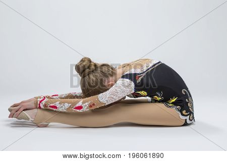Sport Ideas. Young Caucasian Female Rhythmic Gymnast Athlete In Professional Competitive Suit Doing Backbend Stretching Exercise While Posing in Studio Against White. Horizontal Image