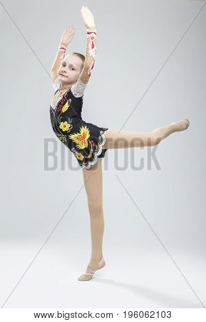 Sport concepts and Ideas. Young Caucasian Female Rhythmic Gymnast Athlete In Professional Competitive Suit Doing Vertical Split Exercise While Posing in Studio Against White. Vertical Image