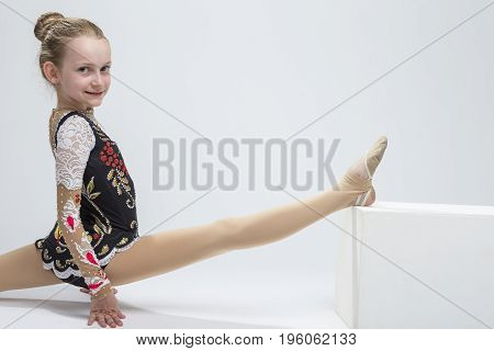 Sport concepts and Ideas. Young Caucasian Female Rhythmic Gymnast Athlete In Professional Competitive Suit Doing Split Exercise While Posing in Studio Against White. Horizonta Image