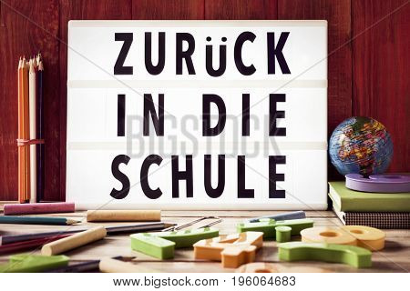 the text zuruck in die schule, back to school in german, in a lightbox placed against a rustic wooden background, surrounded by three-dimensional numbers and chalks and pencils of different colors