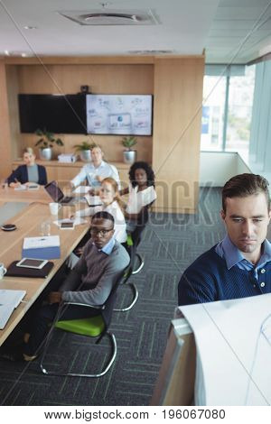 Serious businessman explaining strategy to team in meeting room at office
