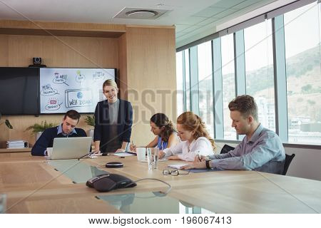 Smiling businesswoman with team working at conference table in meeting room