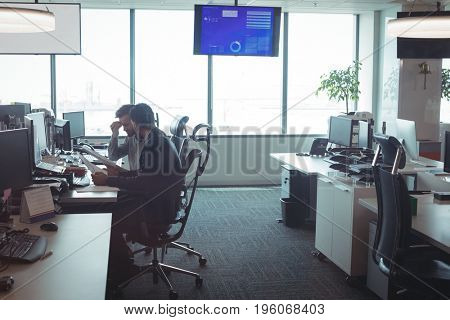 Side view of male business colleagues working together at desk in office