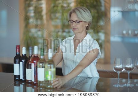 Businesswoman arranging winebottles on table in office
