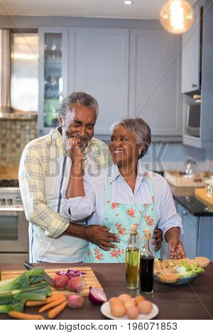 Smiling senior couple preparing food in kitchen