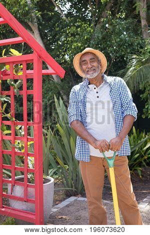 Portrait of man holding equipment while standing in yard