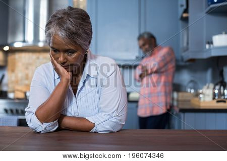 Sad woman with man in background at home