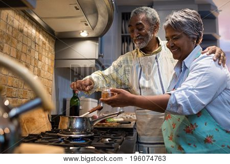 Smiling senior couple preparing food while standing in kitchen at home
