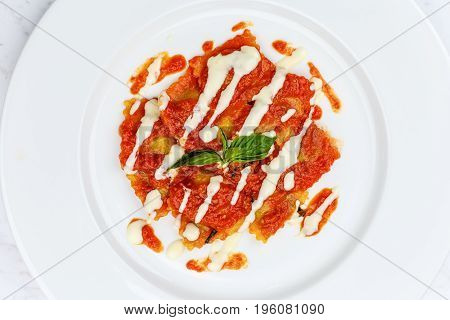 Ravioli with tomato sauce served in white plate on marble serface.