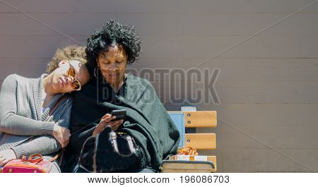Mother and daughter having a rest on a bench after shopping