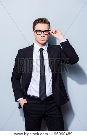 Successful Young Handsome Businessman Banker In A Suit Is Fixing His Glasses, He Stands On Pure Ligh