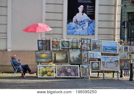 VILNIUS LITHUANIA - JULY 18 2017: Street artists sell paintings to the tourists on the street market in Old Town of Vilnius Lithuania. Vilnius is the capital of Lithuania and its largest city.