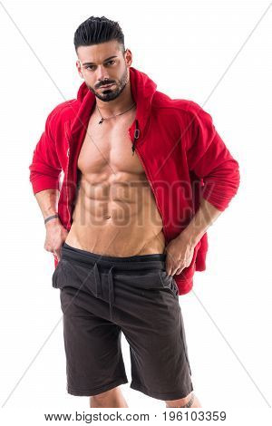 Muscular bodybuilder undressing, opening red hoodie sweater on naked muscle torso on light background