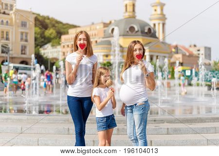 Samesex lesbian family with child on a walk in the park near the fountains. Lesbians mothers with adopted child, happy family, pregnant couple with kid
