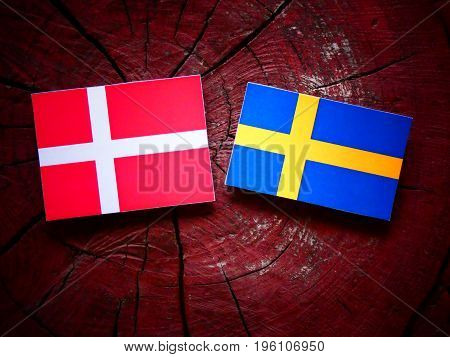 Danish Flag With Swedish Flag On A Tree Stump Isolated