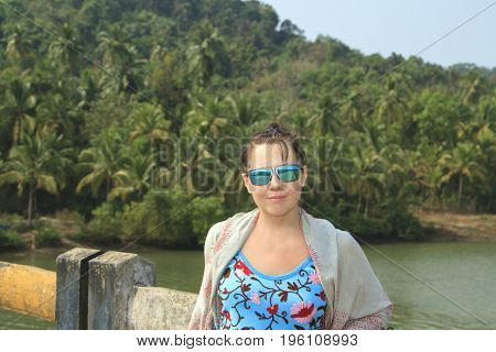 Beautuful girl posing on the brige near tropical forest