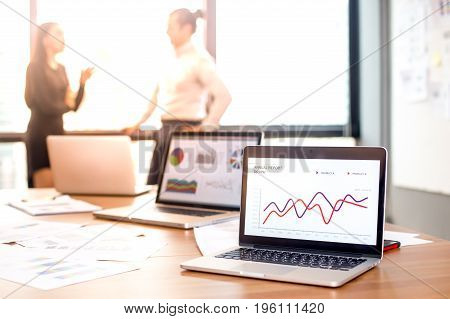 Close-up Of Laptop With Lcd Display On Wall Showing Chart On Desk At Office Meeting Room. People Wor