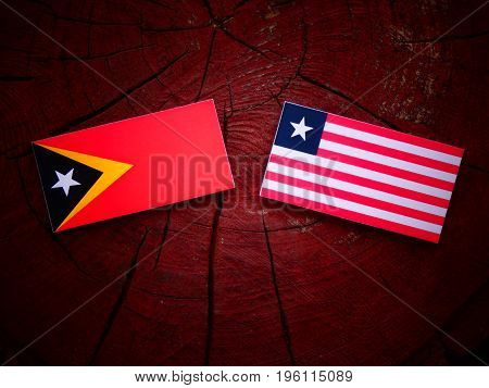 East Timorese Flag With Liberian Flag On A Tree Stump Isolated