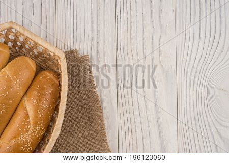Buns in a wicker basket on old wooden table. Top view.