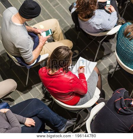 Abowe shot of audience in conference hall. Presentation in lecture hall at university workshop. View of unrecognized participant in audience making notes. Scientific conference event.