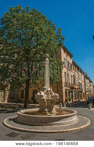 Street with buildings and fountain in sunny afternoon in Aix-en-Provence, a pleasant and lively town in the French countryside. In the Bouches-du-Rhone department, Provence region, southeastern France