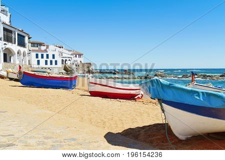 some old fishing boat stranded on the Barques Beach in Calella de Palafrugell, Costa Brava, Catalonia, Spain, with its characteristics white houses with portico in the background