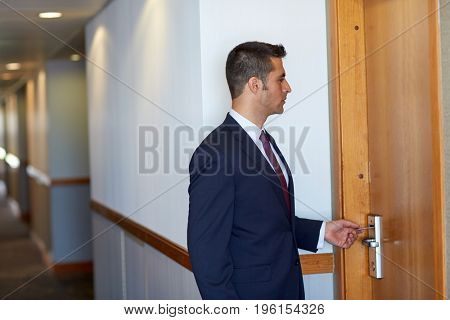 business, security and people concept - businessman with keycard at hotel room or office door