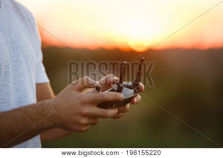 Man holds a drone remote controller in his hands. Close-up of quadcopter RC with antennas during flight. Pilot takes aerial photos and videos with quad