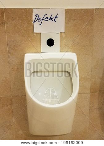 German language hand written sign over a broken urinal