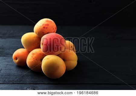 Apricot folded in a heap on a black wooden background