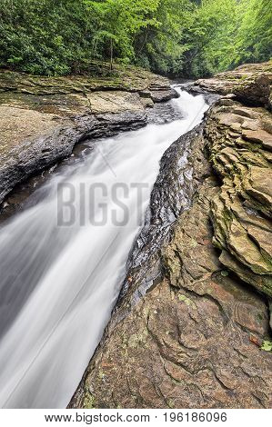 Whitewater flowing through Meadow Run has carved a narrow channel into the rock that is used as a recreational water slide in the Pennsylvania Laurel Highlands forest of Ohiopyle State Park.