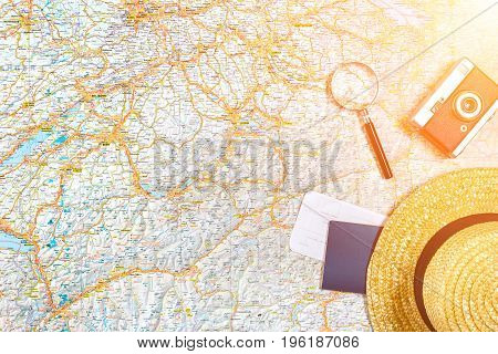 Map of roads with a vintage camera, passport, sunglasses. View from above. The concept of travel. Copy space. Flat lay. Sun flare