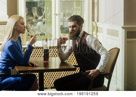 Woman and man drinking from martini glasses. Girl and hipster sharing bottle of wine in restaurant. Couple in love. Alcohol appetizer addictive and convive. Unhealthy lifestyle. Bad habits