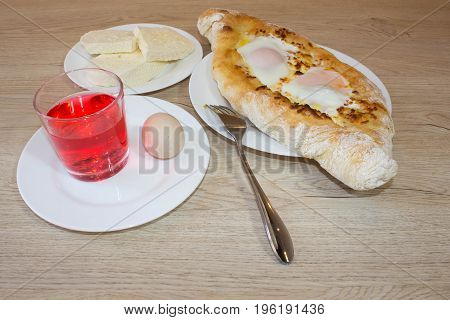 Adjarian khachapuri on a on a plate. Open pie with cheese in the shape of the boat. Delicious homemade khachapuri in Adjarian