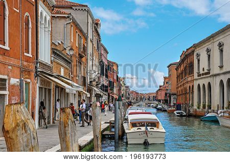 Murano, Italy - May 08, 2013. View of buildings, in front of canal, with people and boats in Murano, a nice little town on top of islands near Venice. Located in the Veneto region, northern Italy