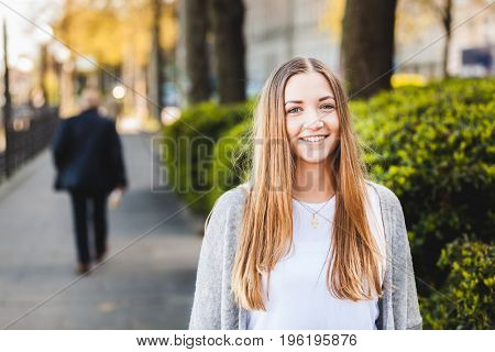 Beautiful blonde girl portrait outdoors. Cheerful young woman looking at camera and smiling. Candid and natural expressions caucasian ethnicity. German girl portrait.
