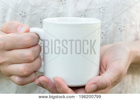 Young caucasian woman holding a white mug mock up blank space for text artwork hands linen shirt natural authentic kinfolk style soft light