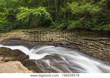 Whitewater flowing through Meadow Run has carved a narrow channel into the rock that is used as a recreational water slide in the Pennsylvania Laurel Highlands forest of Ohiopyle State Park.