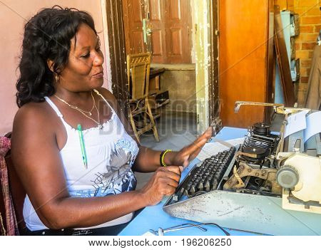 Trinidad de Cuba, Cuba, July 2, 2012;  Cuban typist typing on old fashioned manual typewriter in typical office in Trinidad de Cuba