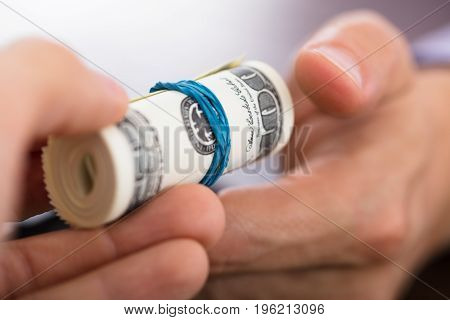Close-up Of A Person Handing Over The Rolled Up Money To Another Hand